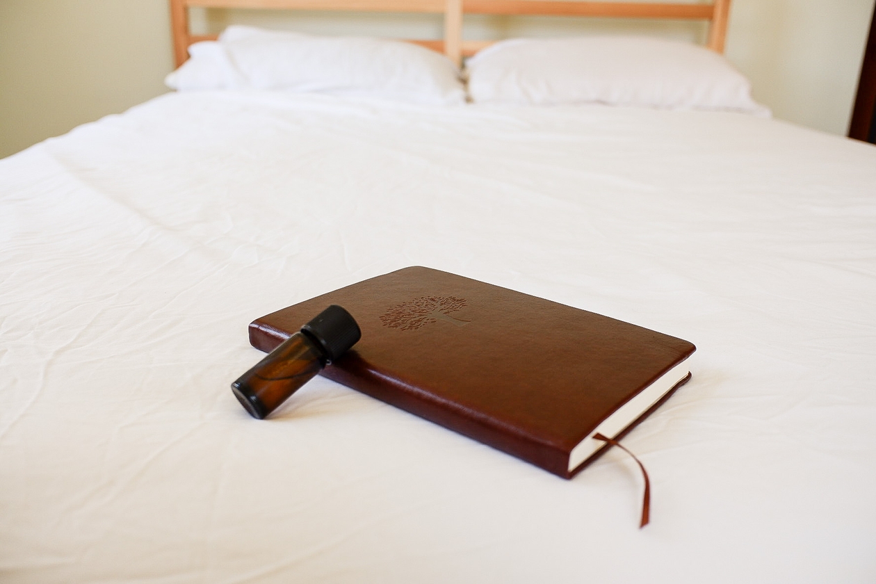 Photo of lavender essential oils, white sheets, journal